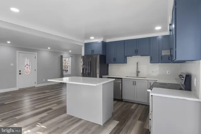 a kitchen with a stove a refrigerator and a sink with wooden floor