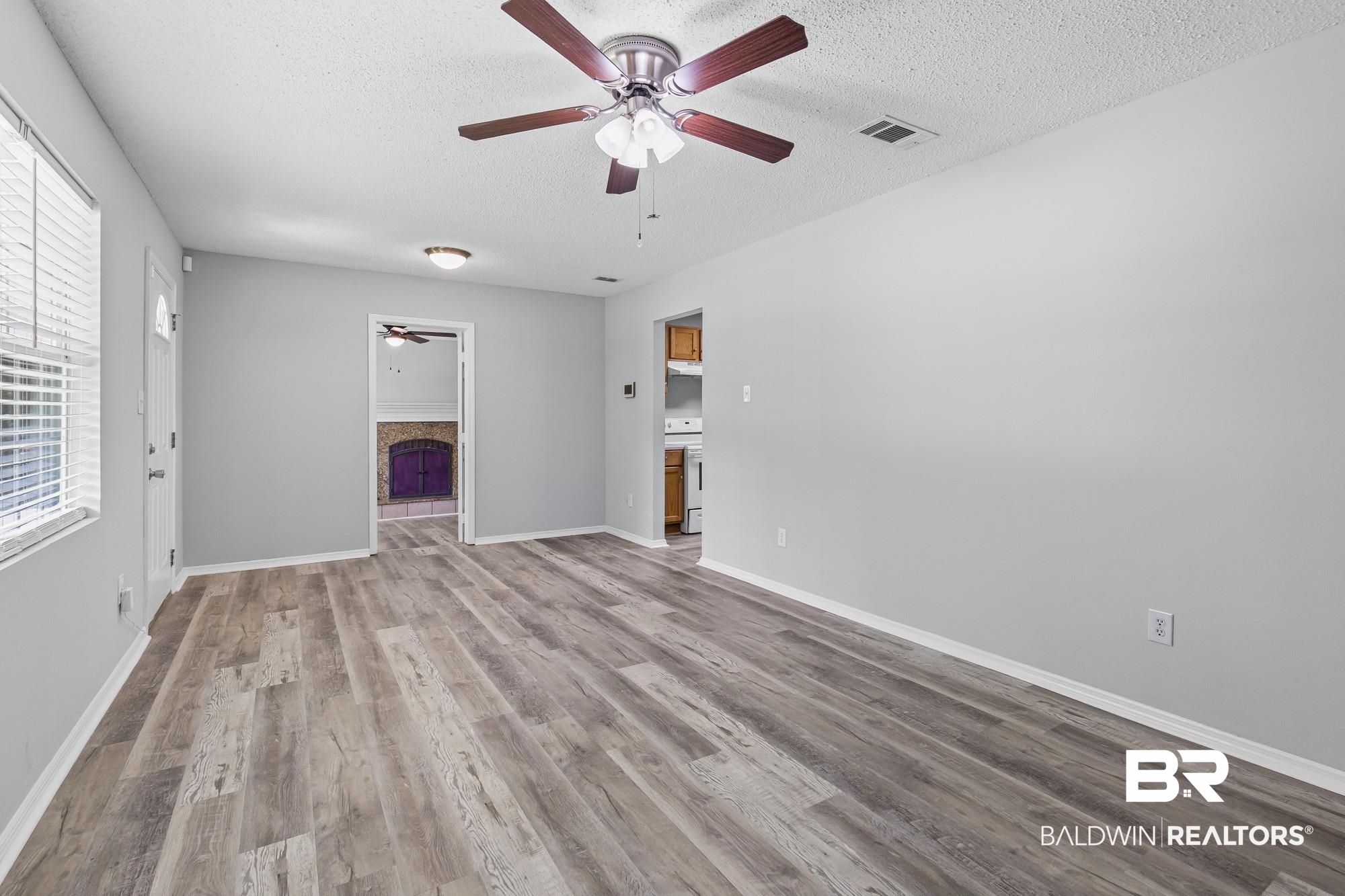 6933 Burbank Court Mobile, AL 36619 - Photo 9 of 25 Bright living space featuring wood-finish flooring, light gray walls, a ceiling fan with integrated lighting, and white trim