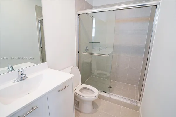 a bathroom with a shower sink vanity mirror and toilet