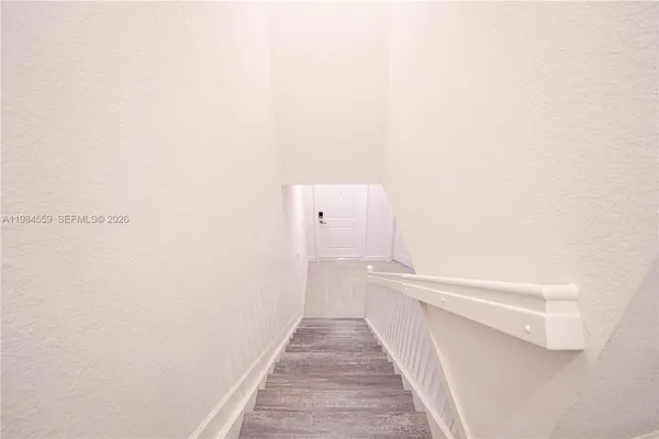 a view of a hallway with wooden floor and a white wall