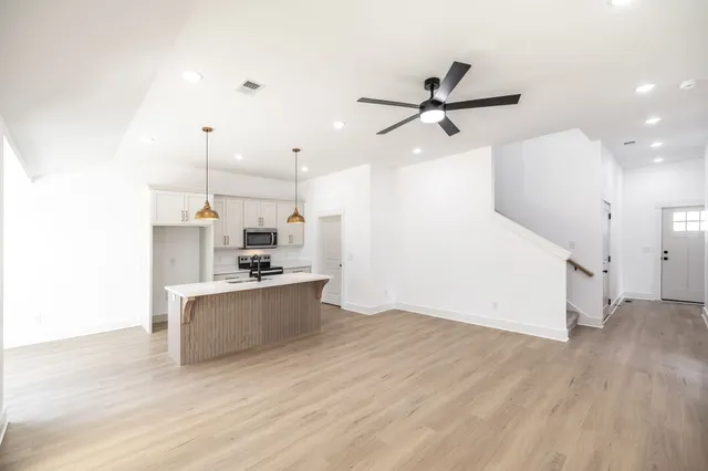 a kitchen with kitchen island a stove a sink and a refrigerator with wooden floor