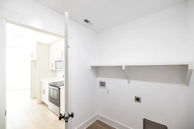 a view of a kitchen with white cabinets and wooden floor