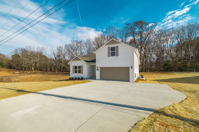 a front view of a house with yard and large trees