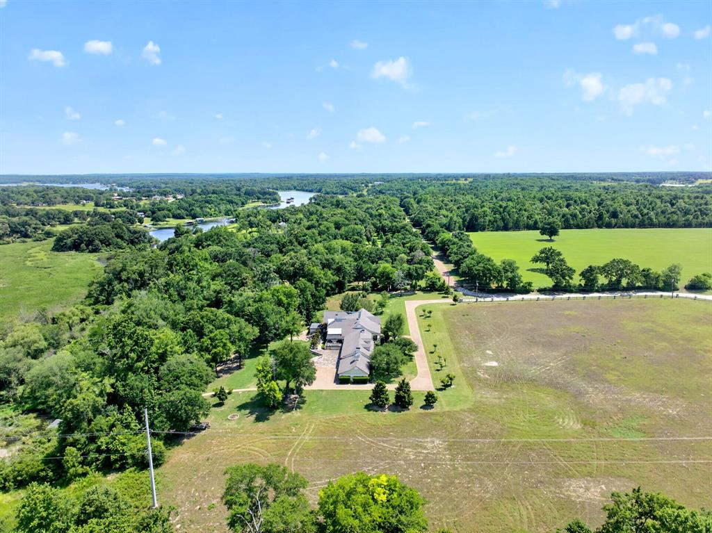 1901 Rose Pointe Athens, TX 75752 - Photo 36 of 37 Spacious property featuring a large residence with an attached garage, extensive surrounding greenery, mature trees, and a distant body of water