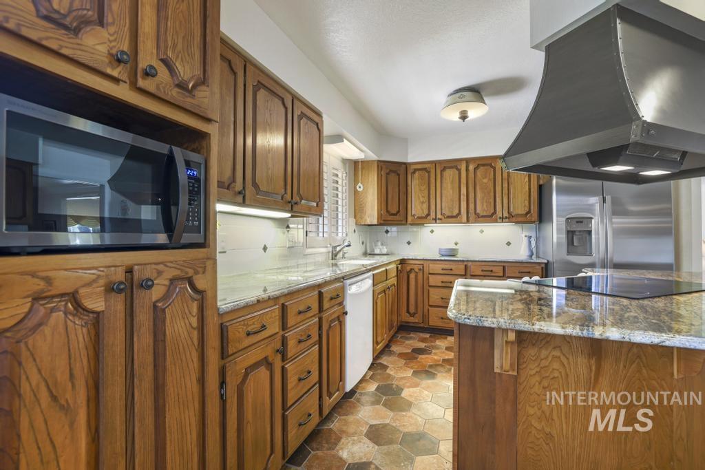 2018 Rancho Vista Drive Twin Falls, ID 83301 - Photo 12 of 50 Kitchen featuring wood cabinetry, an integrated microwave, a built-in cooktop, a stainless steel refrigerator, and a dark metal range hood