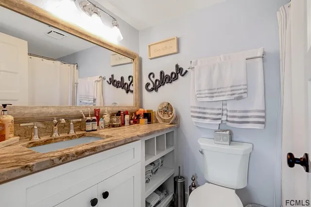 a bathroom with a granite countertop sink mirror vanity and toilet