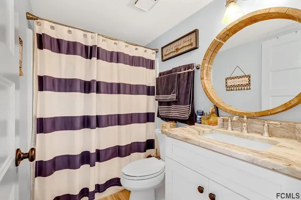 a bathroom with a sink toilet a mirror and shower curtain