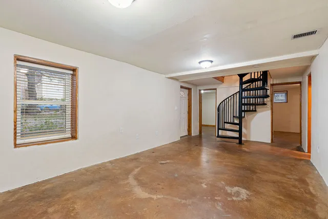 a view of an empty room with stairs and a ceiling fan