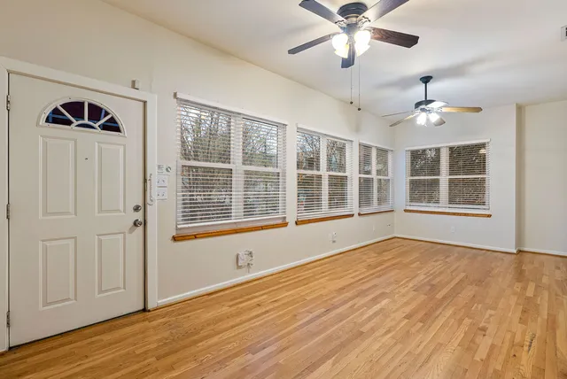 a view of an empty room with wooden floor and a window