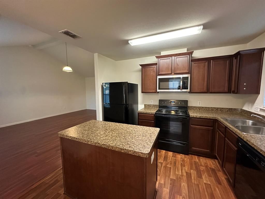 1818 Clegg Street Howe, TX 75459 - Photo 23 of 34 Kitchen featuring dark wood cabinetry, speckled countertops, and black appliances including a refrigerator, range, microwave, and dishwasher