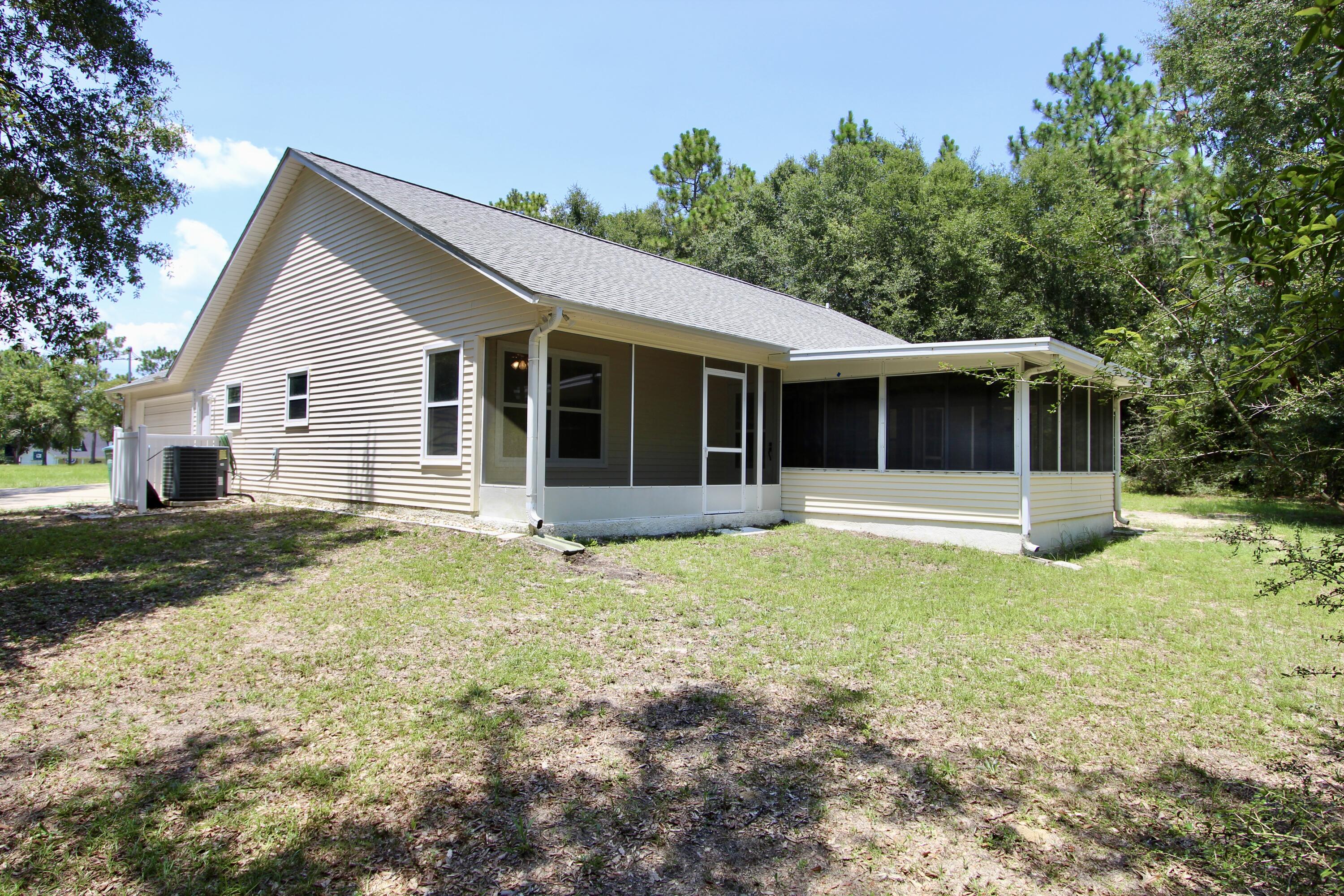 1088 Tallokas Road Crestview, FL 32536 - Photo 16 of 16 a house that has a big yard and large trees with wooden fence