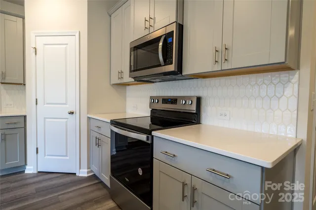 a kitchen with stainless steel appliances white cabinets and a stove top oven
