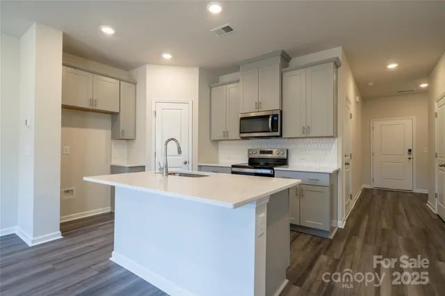 a kitchen with kitchen island a sink stainless steel appliances and cabinets