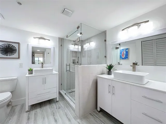a bathroom with a sink a toilet a mirror and shower