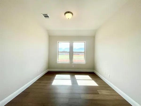 a view of empty room with wooden floor and fan