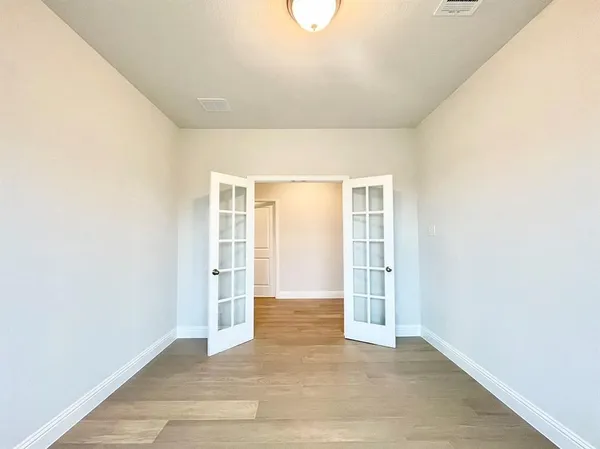 an empty room with wooden floor and windows