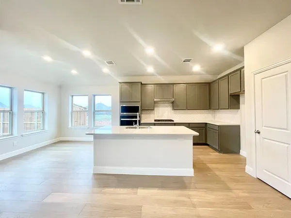 a large white kitchen with kitchen island a sink a stove and a refrigerator