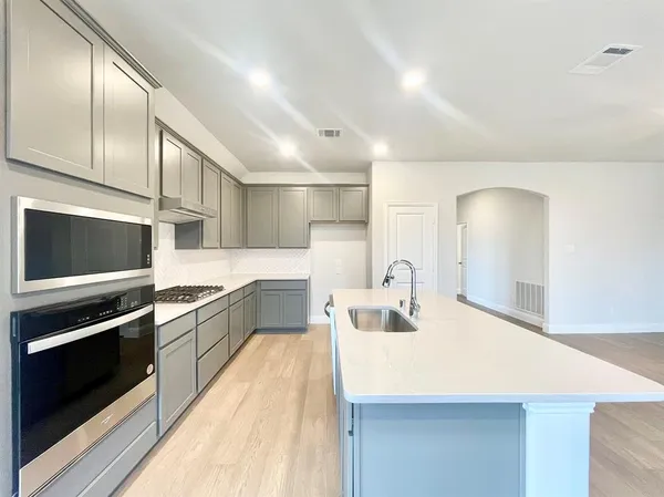 a large kitchen with stainless steel appliances wooden floor and a counter top space