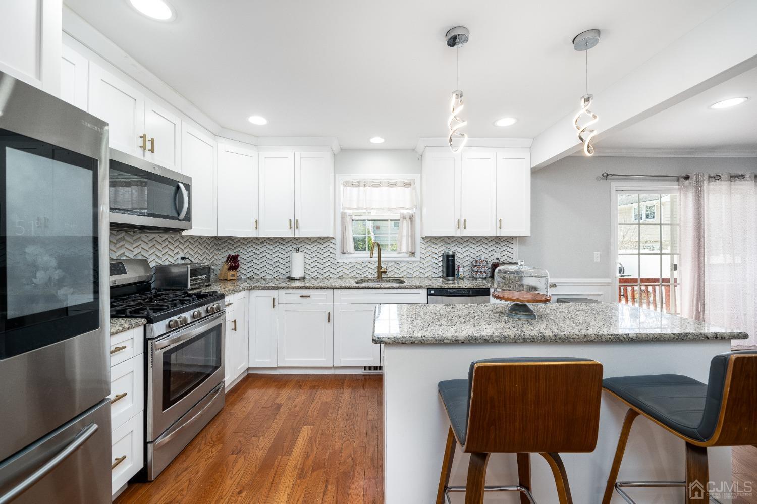 5 Glen Gary Road Middlesex, NJ 08846 - Photo 10 of 37 a kitchen with stainless steel appliances granite countertop a stove top oven a sink dishwasher a dining table and chairs with wooden floor