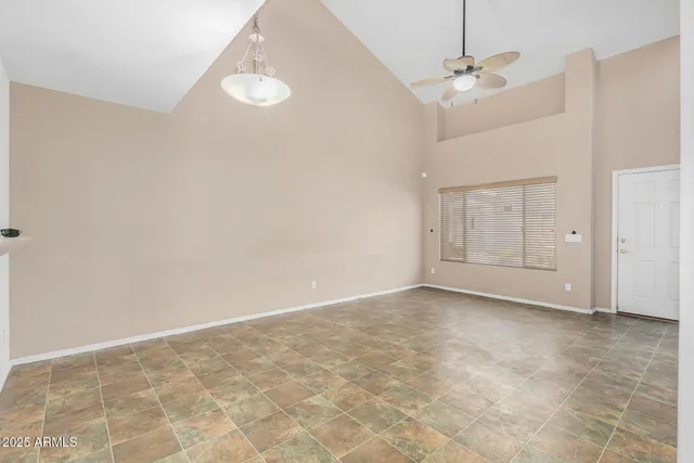 an empty room with chandelier fan and windows