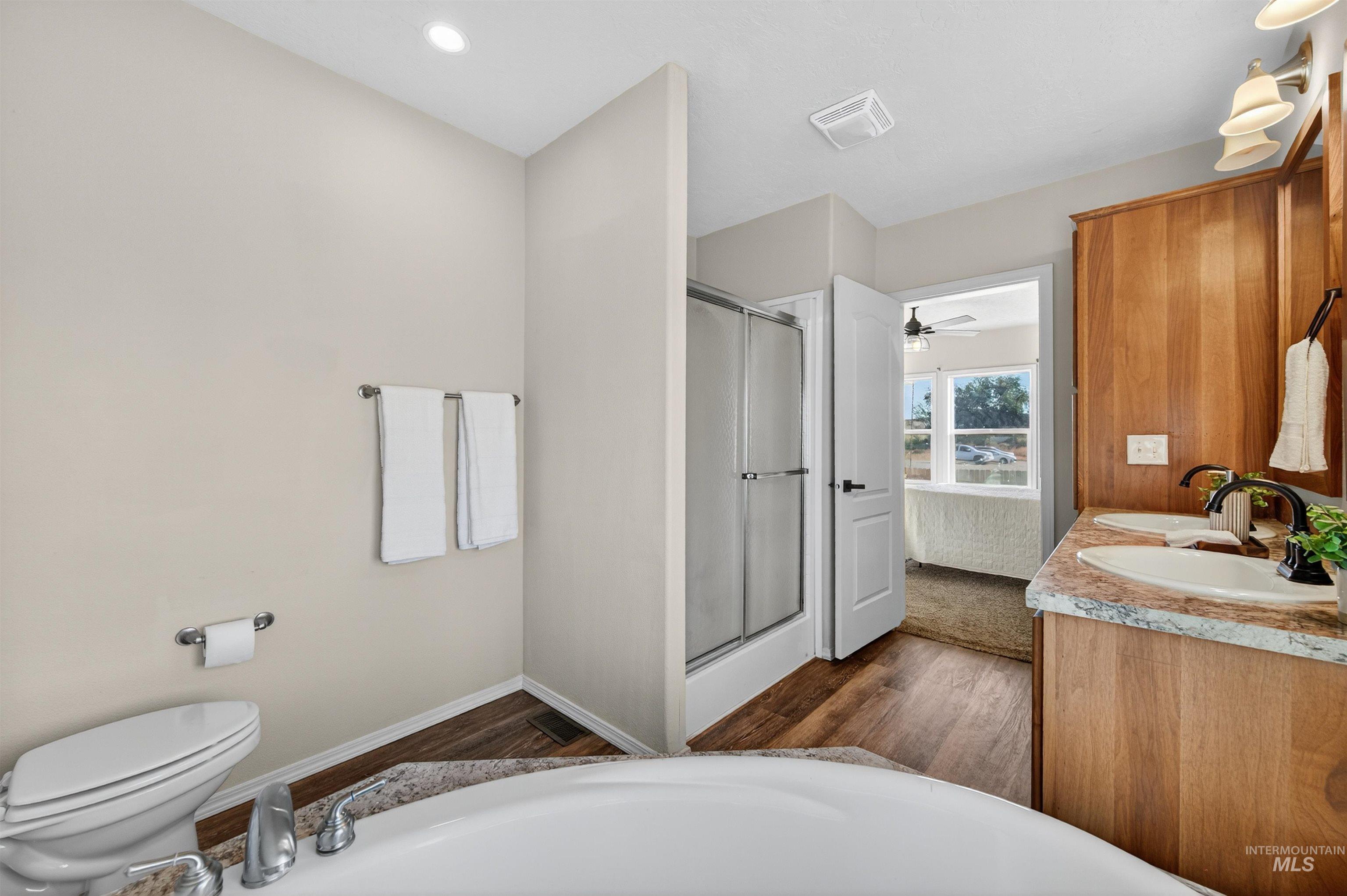 1203 Locker Avenue Parma, ID 83660 - Photo 26 of 49 Full bathroom with double vanity, connected bathroom, a stall shower, dark wood-style floors, and recessed lighting