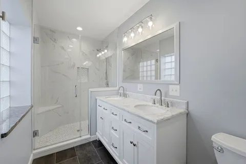 a bathroom with a double vanity sink mirror and shower