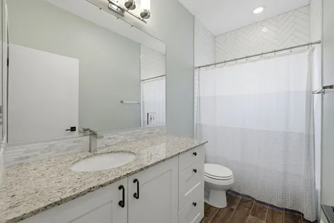 a bathroom with a granite countertop sink toilet and shower