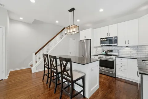 a kitchen with stainless steel appliances granite countertop a kitchen island hardwood floor and a sink