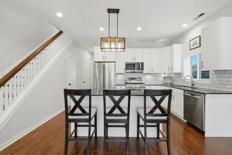 a kitchen with stainless steel appliances a dining table chairs microwave and cabinets