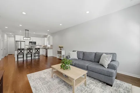 a living room with furniture and kitchen view with wooden floor