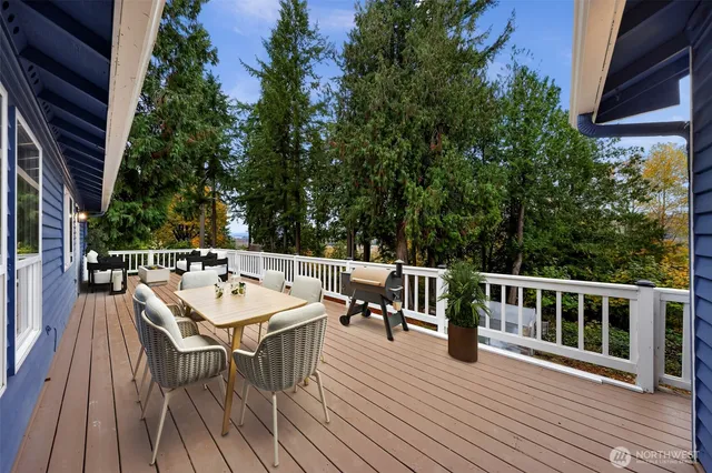 a view of a roof deck with table and chairs a barbeque with wooden floor and fence