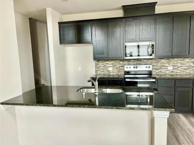 a kitchen with stainless steel appliances granite countertop a sink and a stove