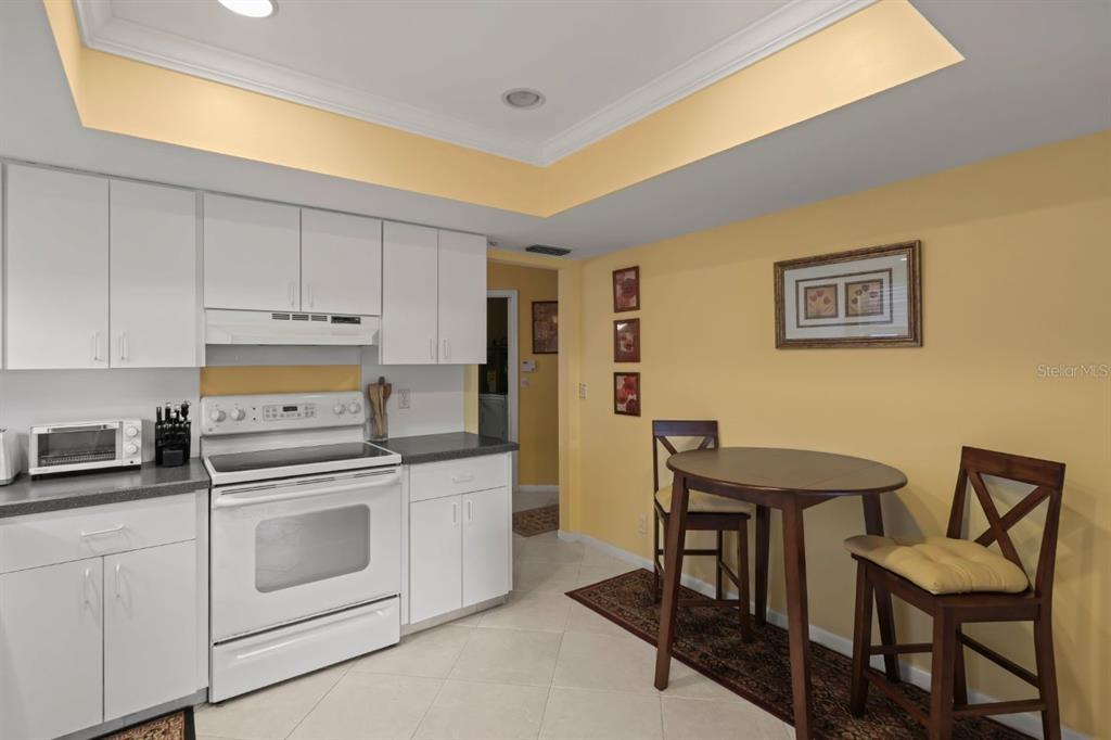 10618 180th Place South Boca Raton, FL 33498 - Photo 14 of 45 a kitchen with stainless steel appliances granite countertop a stove a refrigerator white cabinets and chairs