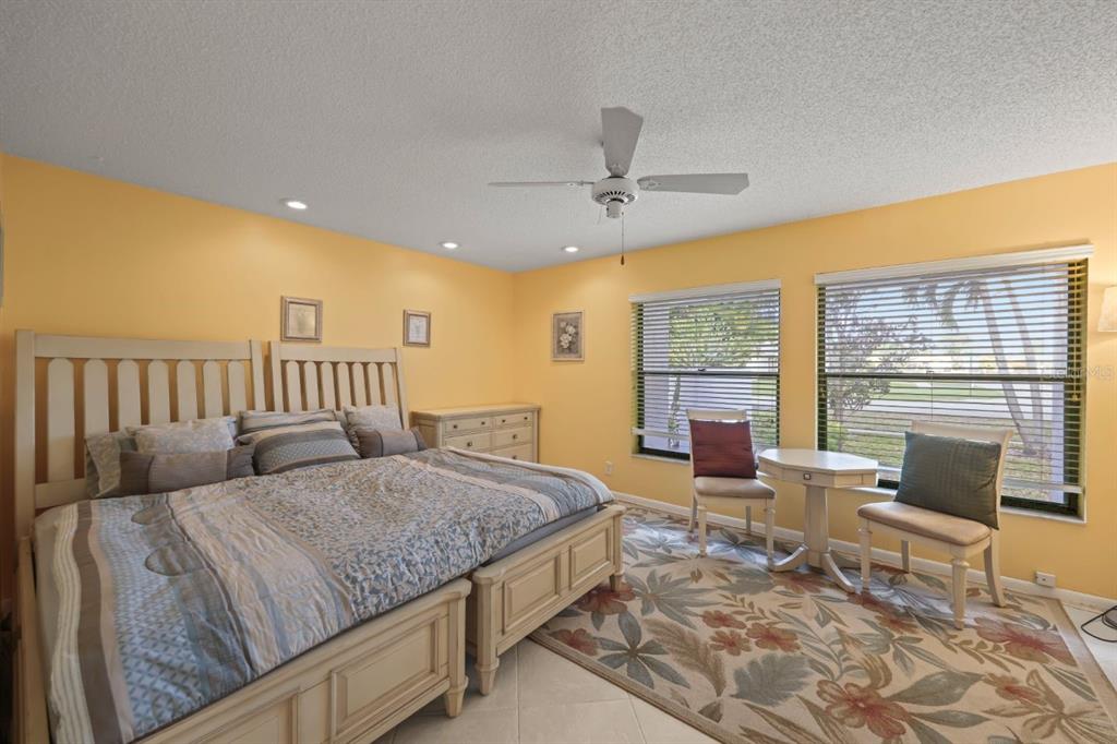 10618 180th Place South Boca Raton, FL 33498 - Photo 22 of 45 a spacious bedroom with a bed a chandelier and large window