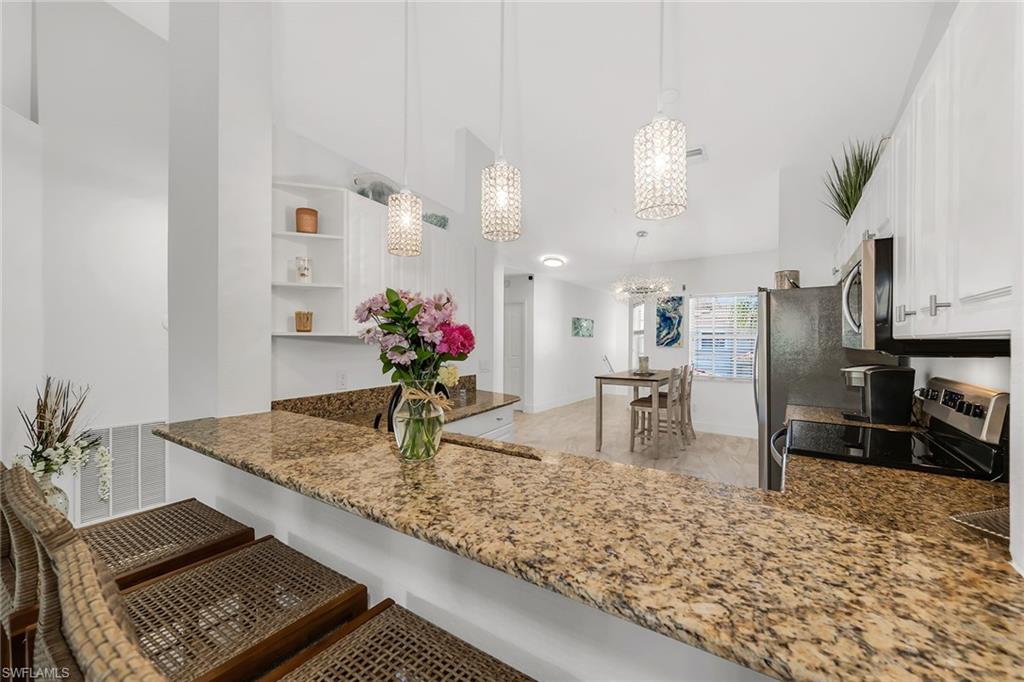 1747 Reuven Circle, Unit 4 Naples, FL 34112 - Photo 13 of 46 a kitchen with kitchen island granite countertop a sink stove and refrigerator