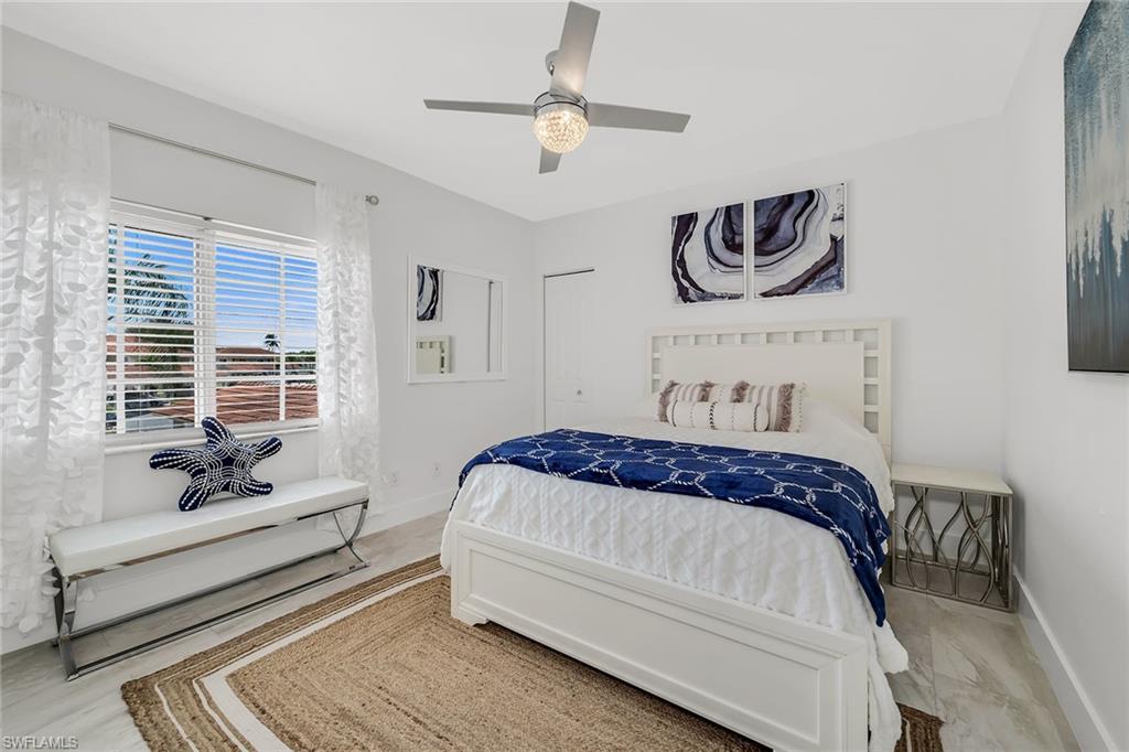 1747 Reuven Circle, Unit 4 Naples, FL 34112 - Photo 21 of 46 a bedroom with a bed and a chandelier