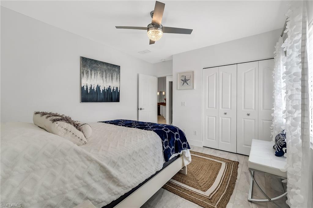 1747 Reuven Circle, Unit 4 Naples, FL 34112 - Photo 22 of 46 a bedroom with a bed and a chandelier