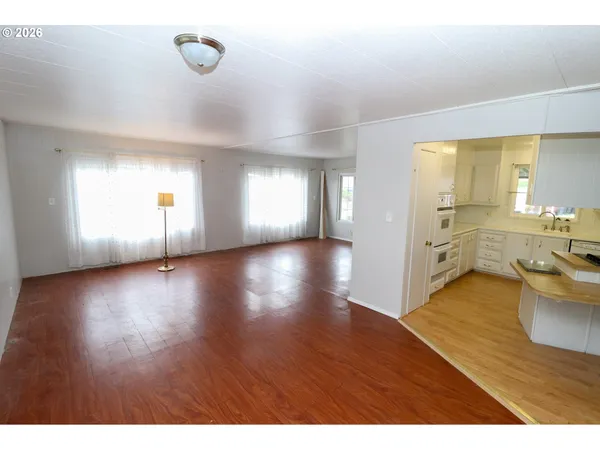 a view of an empty room with window and wooden floor
