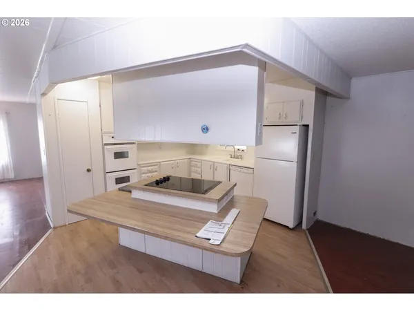 a kitchen with a refrigerator and a wooden floor