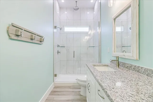 a bathroom with a granite countertop toilet a sink and a window