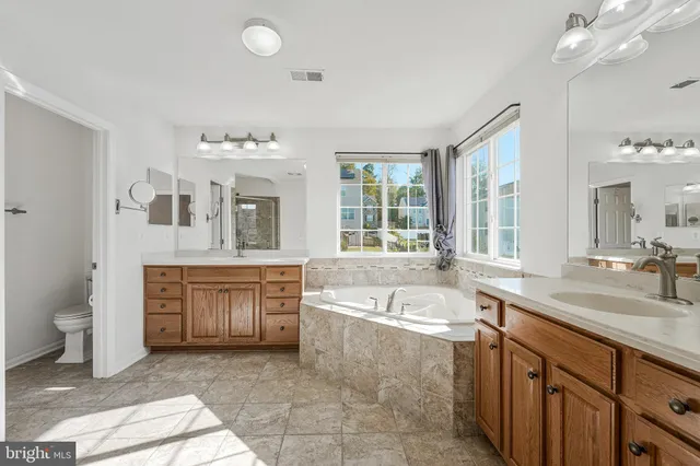 a spacious bathroom with a tub sink and mirror