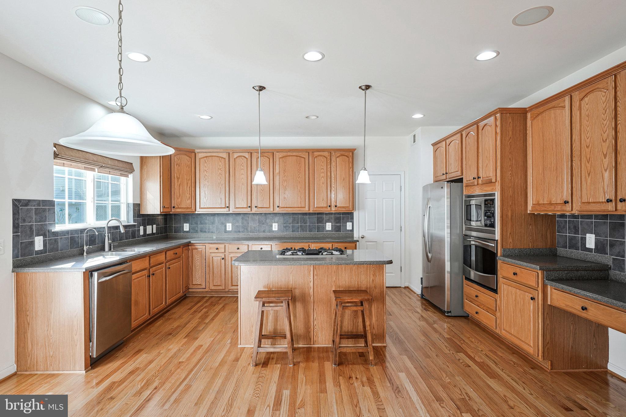 16012 Imperial Eagle Court Woodbridge, VA 22191 - Photo 4 of 25 a kitchen with stainless steel appliances a stove a sink a refrigerator a center island and a wooden floor