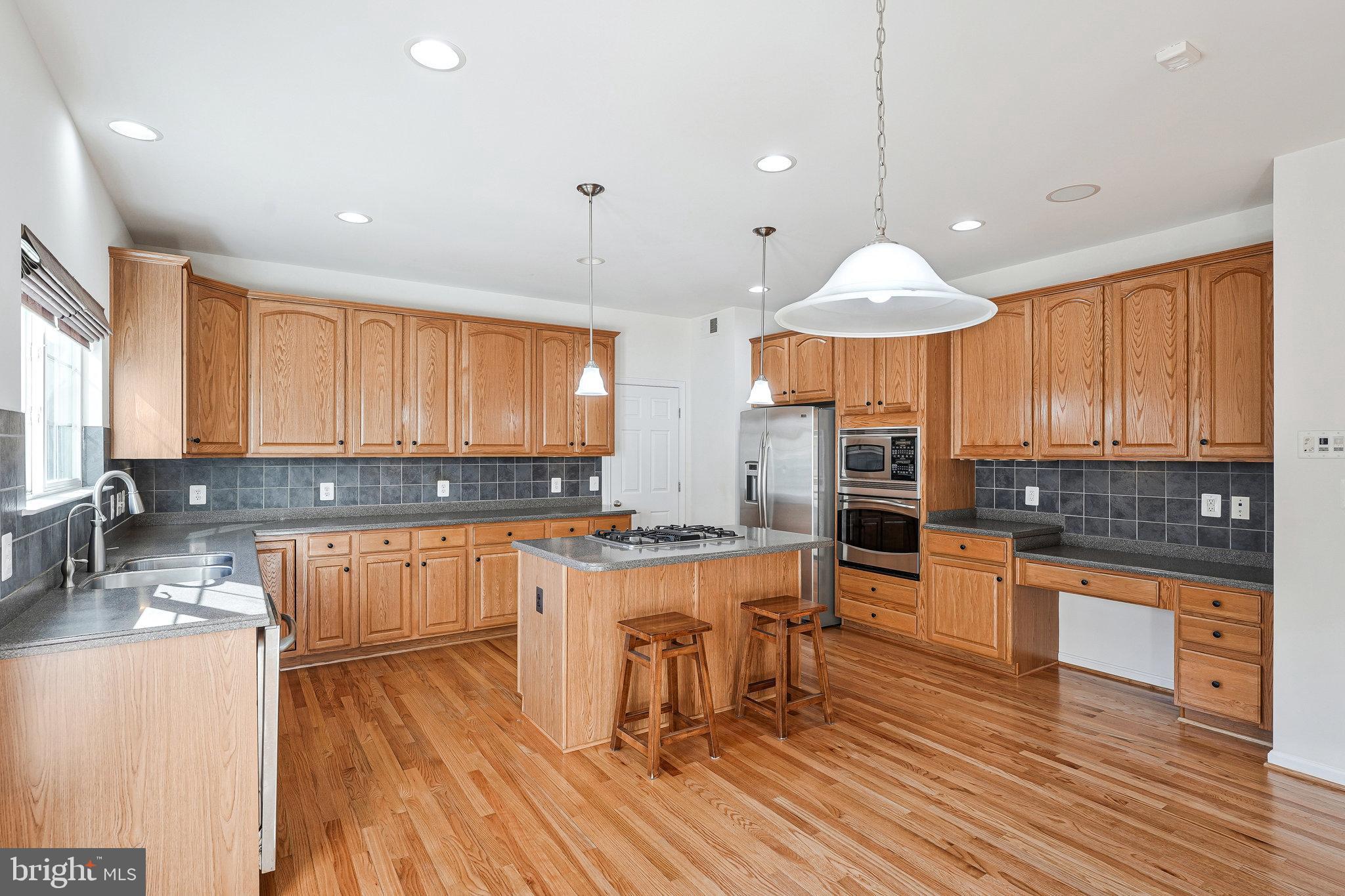 16012 Imperial Eagle Court Woodbridge, VA 22191 - Photo 9 of 25 a kitchen with stainless steel appliances granite countertop wooden cabinets a stove and a wooden floors