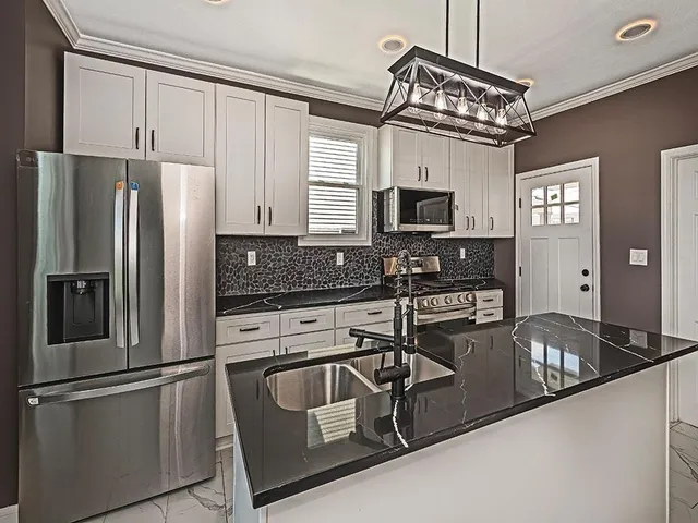 a kitchen with stainless steel appliances granite countertop a refrigerator a stove and a sink with wooden floor