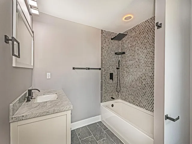 a bathroom with a granite countertop sink a toilet and shower