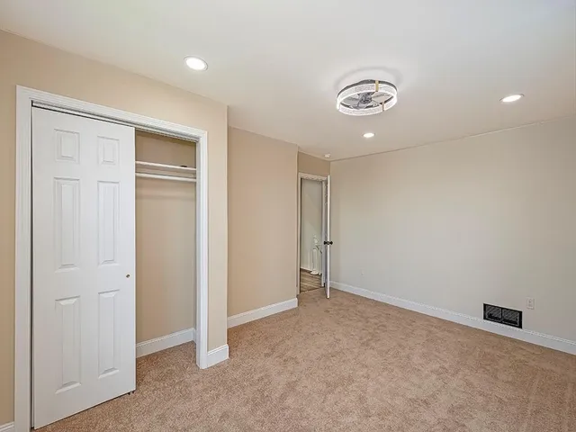 an empty room with closet and a chandelier fan