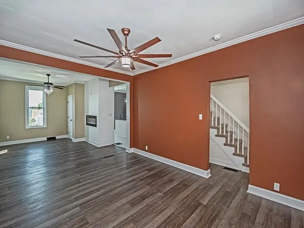 a view of an empty room with wooden floor and a ceiling fan
