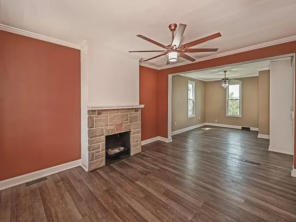 a view of an empty room with wooden floor fireplace and a window