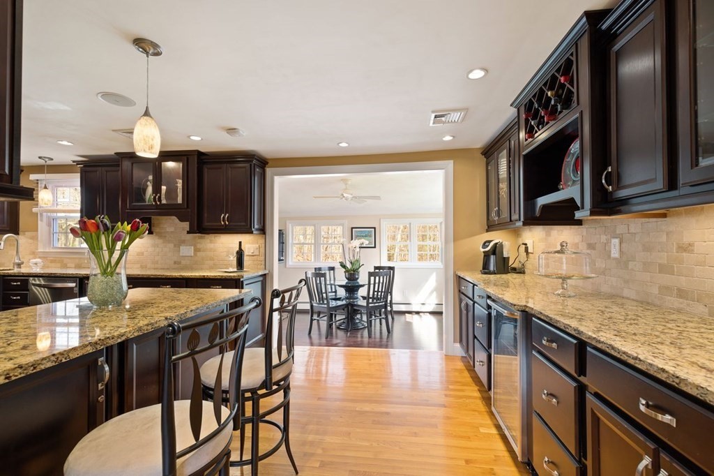 22 Kennedy Road Sharon, MA 02067 - Photo 9 of 41 a kitchen with stainless steel appliances granite countertop a stove top oven a sink a dining table and chairs with wooden floor