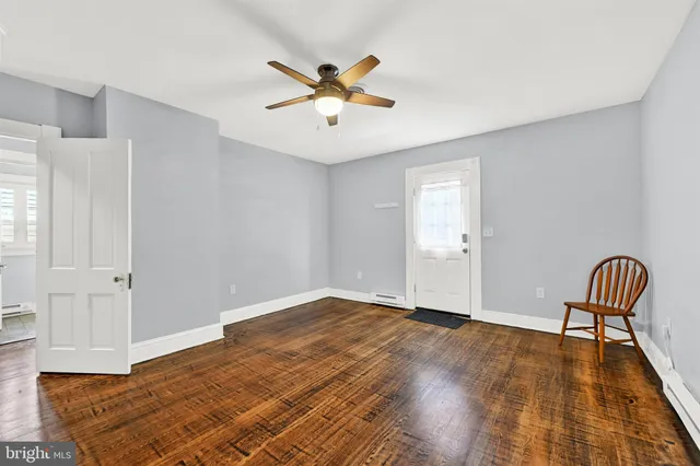an empty room with wooden floor chandelier fan and windows